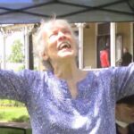 An old woman raising her hands while singing