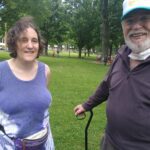 An old man wearing a cap standing beside a woman